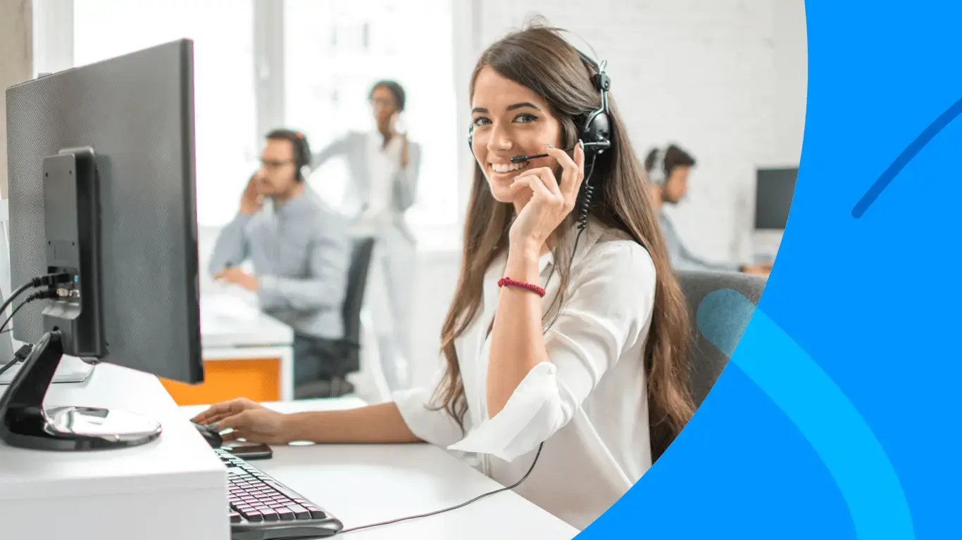 Smiling contact center agent wearing a headset and working at the computer desk in professional office environment